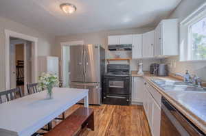 Kitchen featuring appliances with stainless steel finishes, light wood-type flooring, sink, and white cabinetry