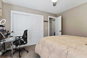 Carpeted bedroom with ceiling fan and a closet