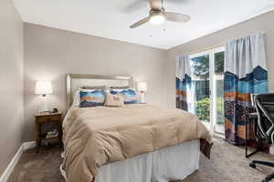 Carpeted bedroom featuring ceiling fan, multiple windows, and access to outside