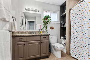 Bathroom featuring tile patterned flooring, vanity, a shower with curtain, and toilet