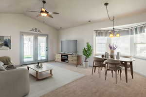 Living room featuring lofted ceiling, ceiling fan with notable chandelier, and light colored carpet