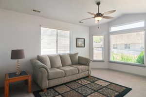 Living room with ceiling fan, carpet floors, and vaulted ceiling