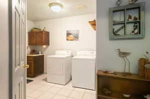 Washroom featuring cabinets, light tile patterned floors, and washer and clothes dryer