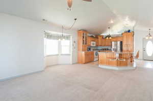 Kitchen with ceiling fan, range, vaulted ceiling, a kitchen island, and light colored carpet