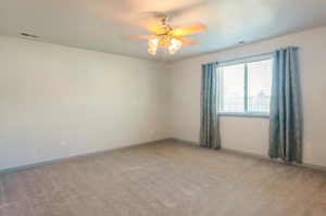 Carpeted empty room featuring ceiling fan