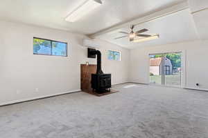 Interior space with a wood stove, lofted ceiling with beams, and carpet