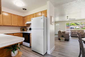 Kitchen with ceiling fan, light hardwood / wood-style flooring, a textured ceiling, and white appliances