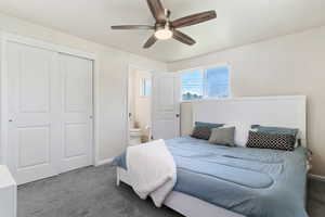 Carpeted bedroom featuring connected bathroom, a closet, and ceiling fan