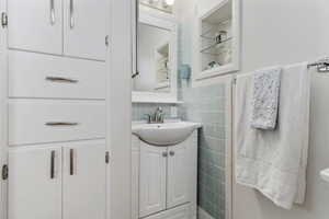 Bathroom featuring tile walls, vanity, and decorative backsplash