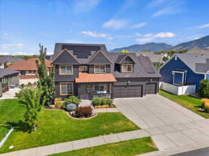 View of front of home featuring a front lawn, a mountain view, solar panels, and a garage