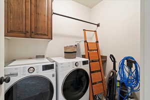 Laundry room with separate washer and dryer and cabinets