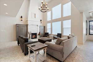 Living room with a textured ceiling, a fireplace, a notable chandelier, and a high ceiling