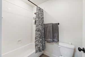 Bathroom featuring shower / bath combo, toilet, and tile patterned floors