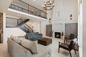 Living room featuring a towering ceiling, a fireplace, and a chandelier