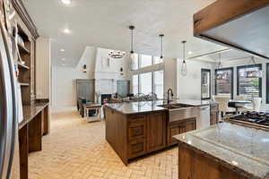 Kitchen with a center island with sink, stainless steel appliances, hanging light fixtures, and a healthy amount of sunlight