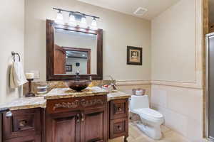 Bathroom with vanity, tile walls, toilet, and tile patterned flooring