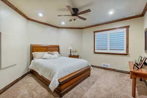 Carpeted bedroom featuring ornamental molding and ceiling fan