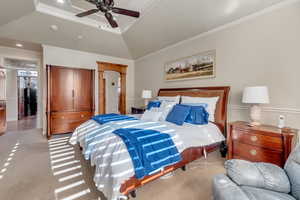 Bedroom with lofted ceiling, ceiling fan, a raised ceiling, crown molding, and light colored carpet