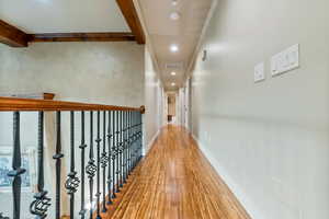 Second level corridor with hardwood / wood-style floors, crown molding, and beam ceiling