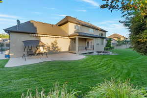 Rear view of house with a patio area and a yard