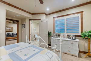 Carpeted bedroom with ornamental molding and ceiling fan