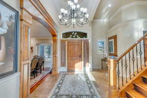 Foyer entrance with a notable chandelier, crown molding, a towering ceiling, and tile patterned floors