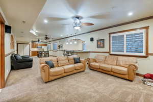 Living room with ornamental molding, light colored carpet, and ceiling fan