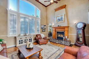 Living room featuring ceiling fan, light hardwood flooring, plenty of natural light, 2 story ceiling and gorgeous two-sided fireplace