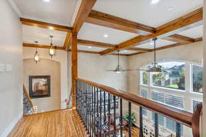 Hallway with coffered ceiling, crown molding, light hardwood flooring, and beamed ceiling