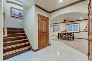 Stairs featuring ceiling fan, ornamental molding, and tile patterned floors