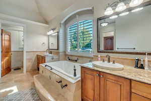 Bathroom with tiled bath, tile patterned floors, lofted ceiling, tile walls, and dual bowl vanity