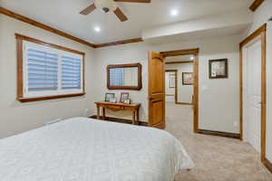 Carpeted bedroom with crown molding and ceiling fan