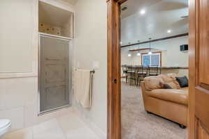 Bathroom with a shower with shower door, ornamental molding, tile patterned flooring, and toilet