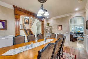 Formal dining space with a notable chandelier, ornamental molding, decorative columns, and light tile patterned flooring