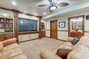 Carpeted living room with ceiling fan and decorative columns