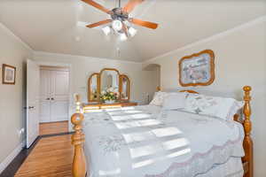 Bedroom with vaulted ceiling, light hardwood  flooring, crown molding, and ceiling fan