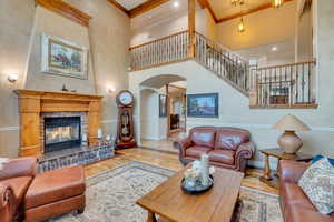 Living room featuring light hardwood / wood-style flooring, ornamental molding, a multi sided fireplace, and a high ceiling