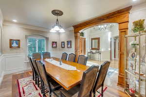 Formal dining room with decorative columns, light hardwood / wood-style flooring, a chandelier, and crown molding