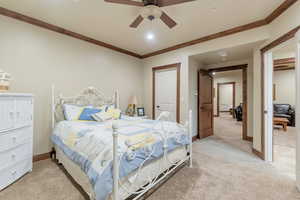 Bedroom with ceiling fan, light colored carpet, and crown molding