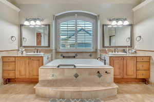 Bathroom with double vanity, tiled tub, and tile patterned flooring