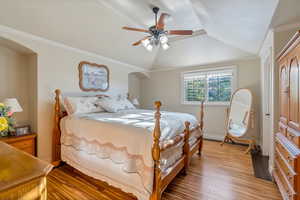 Bedroom with ceiling fan, wood-type flooring, crown molding, and lofted ceiling