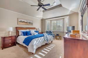 Bedroom featuring ceiling fan, crown molding, light colored carpet, and a tray ceiling