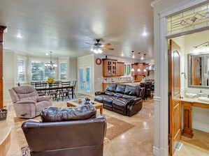 Second living room space featuring light tile patterned floors, sink, ceiling fan with notable chandelier, and ornamental molding and half bath on main level