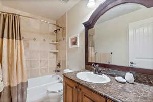 Full bathroom with shower / bath combo with shower curtain, vanity, and toilet