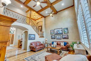 Living room with coffered ceiling, light wood-type flooring, ceiling fan, a high ceiling, and beamed ceiling