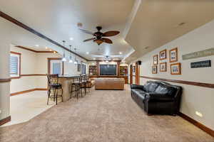 Carpeted living room with ceiling fan and ornamental molding