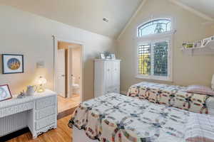 Bedroom featuring light hardwood / wood-style flooring, crown molding, connected bathroom, and high vaulted ceiling