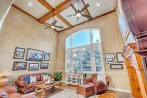 Living room featuring ceiling fan, beam ceiling, a high ceiling, coffered ceiling, and hardwood floors