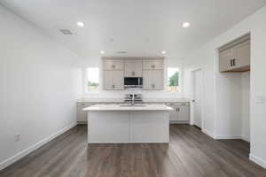 Kitchen featuring gray cabinetry, dark hardwood / wood-style flooring, stainless steel appliances, and a kitchen island with sink