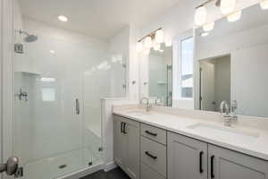 Bathroom with double sink vanity, walk in shower, and tile patterned floors